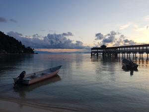 a boat sitting on the water next to a pier at Ombak Dive Resort Perhentian Island in Perhentian Islands