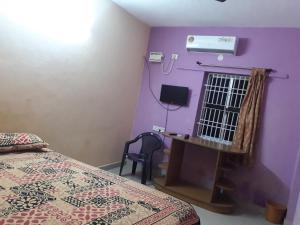 a bedroom with a bed and a window with a fan at Arun Cottages in Mahabalipuram +8 photos