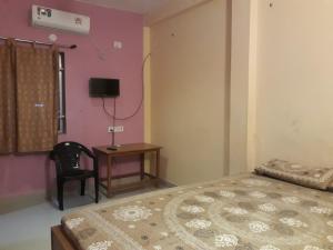 a bedroom with a bed and a table and a chair at Arun Cottages in Mahabalipuram