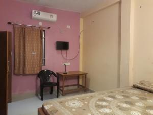 a bedroom with a bed and a table and a chair at Arun Cottages in Mahabalipuram