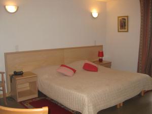 a bedroom with a bed with two red pillows on it at Hôtel Les Pavillons du Golf in Évian-les-Bains +19 photos