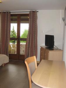 Habitación con mesa, TV y ventana. en Hôtel Les Pavillons du Golf, en Évian-les-Bains