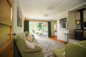 a living room with two couches and a tv at Mahaanui Cottage Farmstay in Tiniroto