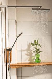 une douche dans une salle de bains avec une plante sur une étagère dans l'établissement Lak Tented Camp, à Lien Son