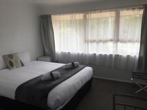 Un dormitorio con una cama grande y una ventana en Fairway Motel & Apartments, en Wanaka