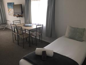 Fairway Motel & Apartments في واناكا: غرفة فندقية بسرير وطاولة مع كراسي