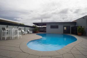 a swimming pool with a blue roof and blue walls at Acacia Motor Inn in Bundaberg