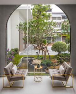 a room with two chairs and a table and a large window at De Princess Hotel Udonthani in Udon Thani