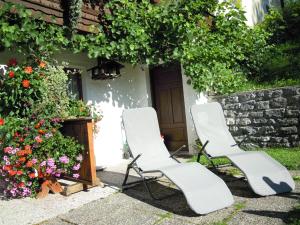 two white chairs sitting in front of a house with flowers at Ferienhaus Höchhäusl in Werfenweng
