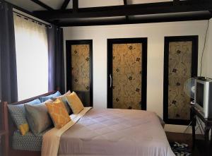 a bedroom with a bed and two windows and a tv at Phu View Hideaway in Ban Kham Proi