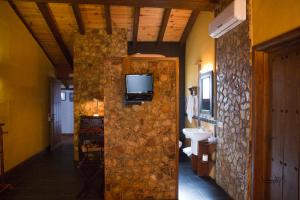 a bathroom with a sink and a tv on a stone wall at La Casona del Abuelo Parra in Villanueva de los Infantes
