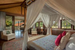 a bedroom with a canopy bed and a living room at Jeeva Saba Bali in Saba