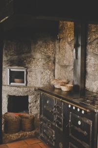 a stone kitchen with a stove and a microwave at Casa da Cresso in Amares