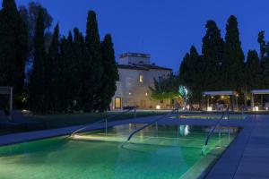 a swimming pool at night with a building and trees at URH - Hotel Molí del Mig in Torroella de Montgrí