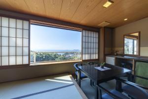 une salle à manger avec une table et une grande fenêtre dans l'établissement Hiranoya, à Gamagori