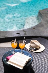 a table with two glasses of orange juice and a book at Kokotel Khao Lak Lighthouse in Khao Lak
