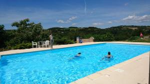 2 personnes nagent dans une piscine bleue dans l'établissement Hotel La Bastie d'Urfé, à Naussac