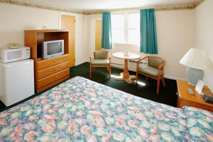 a hotel room with a bed and a tv and a table at Majestic Hotel & Apartments in Ocean City