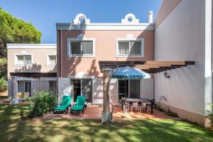 a house with a patio with chairs and an umbrella at Quinta Golf & Beach House in Quinta do Lago