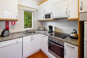 a kitchen with white cabinets and a sink at Quinta Golf & Beach House in Quinta do Lago