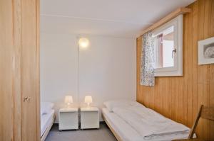 een kleine slaapkamer met 2 bedden en een raam bij Apartment Nussbaum - GRIWA RENT AG in Grindelwald