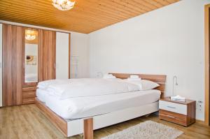 a bedroom with a large white bed and a mirror at Apartment Neuenhaus - GRIWA RENT AG in Grindelwald