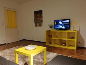 a living room with a yellow table and a tv at Sun Apart Vuorenrinne in Kotka