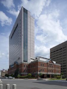 a tall building in front of a brick building at OMO7 Asahikawa by Hoshino Resorts in Asahikawa