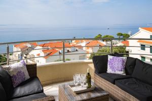 een balkon met 2 banken en een tafel met wijnglazen bij Apartment Toma in Podstrana