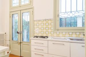 uma cozinha com armários brancos, janelas e um lavatório. em Torre dell'Orologio Apartment em Pádua