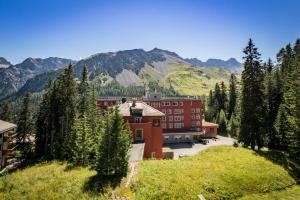 a large red building with mountains in the background at Chalchboda 1 in Arosa