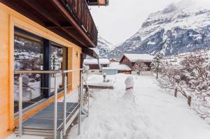 a house covered in snow next to a building at Chic Alpine Apartment for 5 - Perfect for skiers in Grindelwald