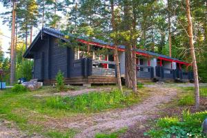 a black cabin with a red roof in the woods at Isotalo Farm at enäjärvi lake in Salo