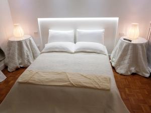 a bed with white sheets and pillows and two lamps at CharmeRooms Palazzo Stampa in Bergamo