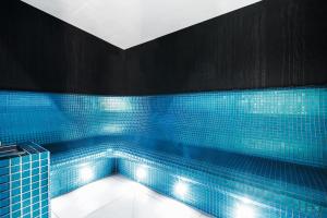 bañera de azulejos azules con luces. en Hotel Testa, en Sopot