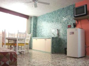 a kitchen with a refrigerator and a table with a television at Suites Angelopolis in Acapulco