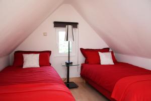 two beds in a room with red sheets and a window at Apartment Sonnenterrasse in Baden-Baden