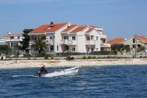 Ein Mann in einem Boot im Wasser in der Nähe von Häusern. in der Unterkunft Villa Punta in Zadar