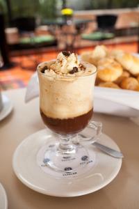 a cup of coffee on a plate on a table at Hotel Estelar Suites Jones in Bogotá +24 photos