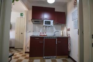eine kleine Küche mit braunen Schränken und einer Mikrowelle in der Unterkunft Vivere la Ciambra in Monreale
