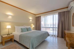 a bedroom with a large bed and a large window at Luna Clube Oceano in Albufeira