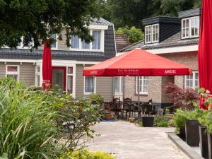 a patio with a red umbrella in front of a house at Hotel-Restaurant Het Rechthuis in Muiderberg