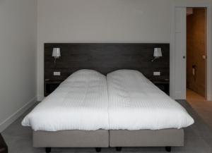 1 cama blanca grande en un dormitorio con 2 luces en Hotel-Restaurant Het Rechthuis en Muiderberg