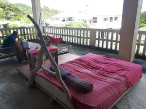 a bed on a porch with a man working on a laptop at backpackers guesthouse Border in Nago