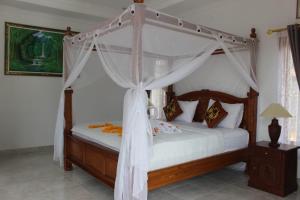 a bedroom with a canopy bed with white curtains at Sekumpul Accommodation in Singaraja