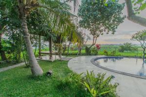 a swimming pool in a garden with a palm tree at Villa D'Carik Bali in Denpasar