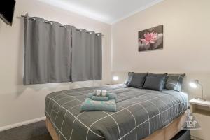 a bedroom with a bed with a blue blanket at Esperance Bay Holiday Park in Esperance