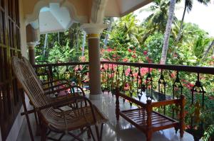 een veranda met 2 stoelen en bloemen bij Ganesh Ayurveda Holiday Home bed and breakfast in Kovalam