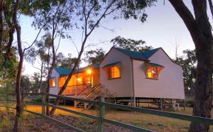 una casa blanca con luces encendidas en un bosque en Accommodation Creek Cottages & Sundown View Suites en Ballandean