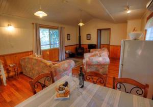 a living room with a table and chairs and a refrigerator at Accommodation Creek Cottages & Sundown View Suites in Ballandean